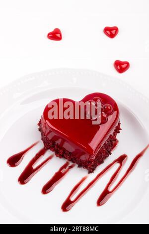 En velours rouge en forme de coeur gâteau décoré avec groseille sur plaque blanche, verticale Vue de dessus Banque D'Images