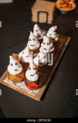 Halloween nourriture et bonbons en forme de citrouilles à une fête, cupcakes fantômes en chocolat Banque D'Images