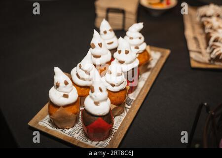 Halloween nourriture et bonbons en forme de citrouilles à une fête, cupcakes fantômes en chocolat Banque D'Images