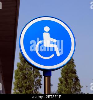 Parking handicapés côté rond - homme en fauteuil roulant sur fond bleu contre indication des places de stationnement commodément près des entrées pour l'accessibilité Banque D'Images