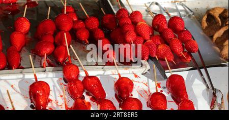 brochettes de fraises caramélisées avec du sucre sur le dessus à vendre dans un étal de bonbons Banque D'Images