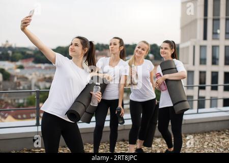 Les Yoginis prennent eux-mêmes des photos sur mobile après des exercices en plein air Banque D'Images