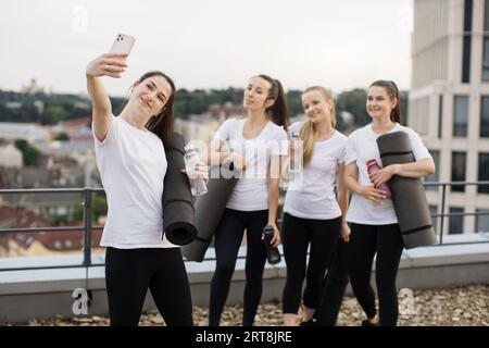 Les Yoginis prennent eux-mêmes des photos sur mobile après des exercices en plein air Banque D'Images