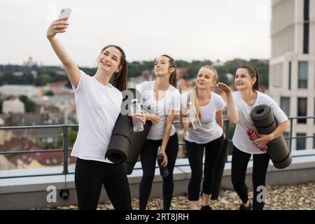 Les Yoginis prennent eux-mêmes des photos sur mobile après des exercices en plein air Banque D'Images