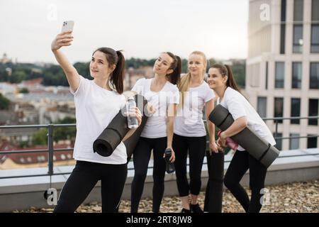 Les Yoginis prennent eux-mêmes des photos sur mobile après des exercices en plein air Banque D'Images