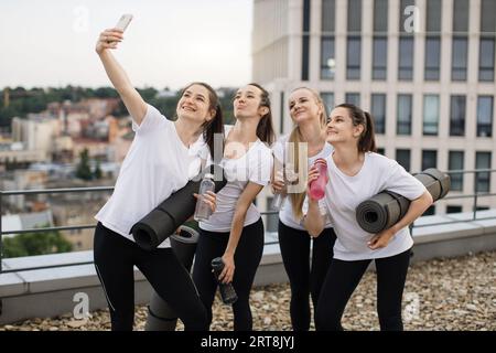 Les Yoginis prennent eux-mêmes des photos sur mobile après des exercices en plein air Banque D'Images