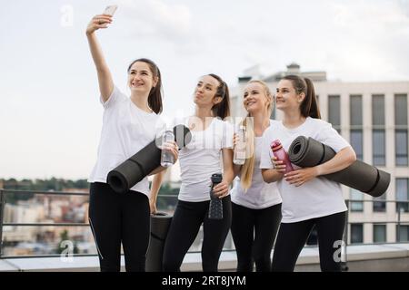 Les Yoginis prennent eux-mêmes des photos sur mobile après des exercices en plein air Banque D'Images