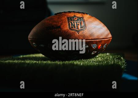 NEW YORK, États-Unis, 11 SEPTEMBRE 2023 : marque de commerce de la NFL : balle en cuir et logo emblématique. Le ballon officiel de la ligue nationale de football place à l'ombre des athlètes Banque D'Images