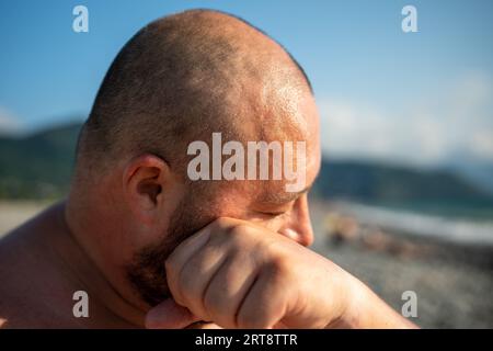 Homme en surpoids frottant la sueur du visage, le front souffrant de chaleur supplémentaire en été. Banque D'Images