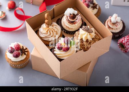 Variété de cupcakes de Noël dans une boîte cadeau avec pain d'épice, canneberge, noix de pécan et chocolat chaud Banque D'Images