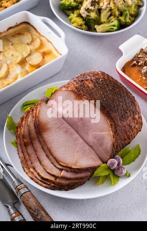 Jambon en tranches en spirale glacé au miel avec des plats d'accompagnement pour un dîner de célébration à Thanksgiving ou Noël Banque D'Images