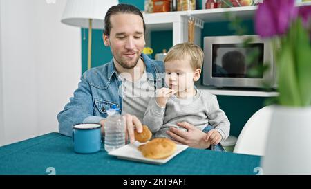 Le père et le fils sont assis sur une table pour prendre le petit déjeuner dans la salle à manger Banque D'Images