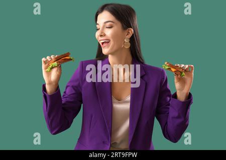 Jeune femme avec des sandwichs savoureux sur fond vert Banque D'Images