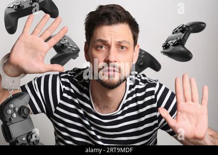 Trouble du jeu. Homme menotté avec gamepad collé à l'écran transparent Banque D'Images