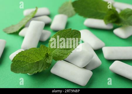 Savoureux chewing-gums blancs et feuilles de menthe sur fond vert, gros plan Banque D'Images