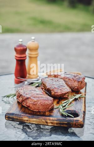 Steaks grillés New-yorkais sur la table en verre dans l'arrière-cour Banque D'Images