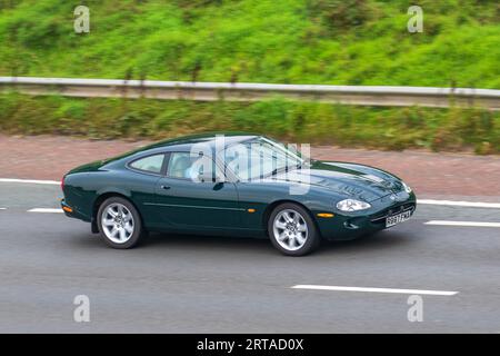 Années 1998 90 Jaguar XK8 V8 Auto Green coupe essence 3996 voyageant à grande vitesse sur l'autoroute M6 dans le Grand Manchester, Royaume-Uni Banque D'Images