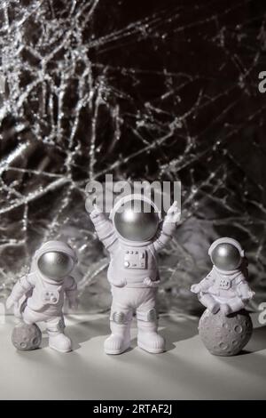 Trois jouets en plastique figurine astronaute sur fond argent espace de copie. Concept de voyage hors terre, vols commerciaux privés de spaceman. Missions spatiales et durabilité Banque D'Images