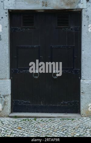 Magnifique grande vieille vieille porte en bois noir de la maison de construction en pierre avec heurtoir décoré avec des sculptures forgées. Architecture, bâtiments historiques, Banque D'Images