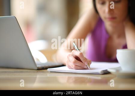 Gros plan portrait d'une femme prenant des notes sur un cahier dans une terrasse de bar Banque D'Images