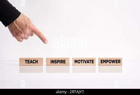 Leadership inspirant et concept d'éducation. Main pointant vers les blocs de bois avec le message enseigner, inspirer, motiver et responsabiliser. Banque D'Images