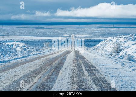 Route glacée menant à travers un paysage désertique enneigé de l'Utah. Banque D'Images