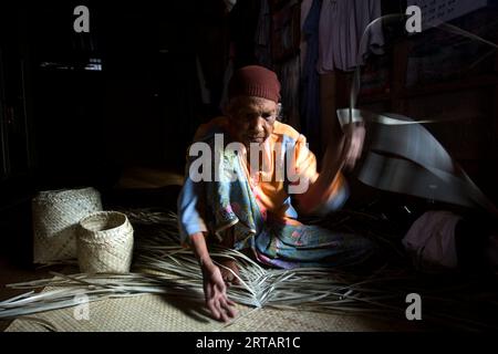 Koh Yao, Thaïlande ; 1 janvier 2023 : une femme âgée prépare un panier avec des feuilles de palmier séchées. Banque D'Images