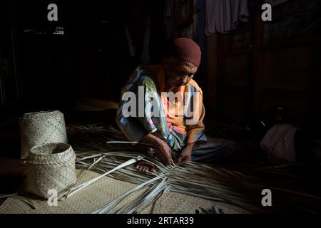 Koh Yao, Thaïlande ; 1 janvier 2023 : une femme âgée prépare un panier avec des feuilles de palmier séchées. Banque D'Images