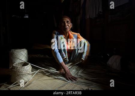 Koh Yao, Thaïlande ; 1 janvier 2023 : une femme âgée prépare un panier avec des feuilles de palmier séchées. Banque D'Images