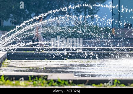 Landshut, Allemagne. 12 septembre 2023. Un passant passe derrière une fontaine par temps ensoleillé. Crédit : Armin Weigel/dpa/Alamy Live News Banque D'Images