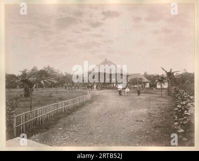 Colonialisme européen en Indonésie, 1900, 1890, vue d'une plantation avec divers bâtiments et un homme et des serviteurs européens au premier plan. Cette photo a probablement été prise à Langkat, Sumatra. Banque D'Images