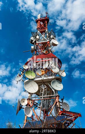 Tour de télécommunication avec antennes avec ciel bleu dans la lumière du soleil du matin, sur la montagne. Banque D'Images