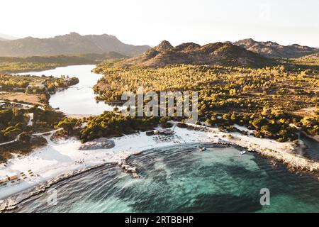 ITALIE, SARDAIGNE 2023 : vue aérienne de la célèbre oasis de Biderosa. Une belle forêt de pins d'Alep et de pins de pierre ainsi qu'une riche végétation spontanée composent la forêt côtière de Bidderosa. Encadré par des genévriers, des chênes-lièges et des chênes verts, un paradis de carte postale s’ouvre, l’un des rares en nombre limité en Sardaigne, avec les couleurs émeraude de la mer et le blanc pur du sable fin. Banque D'Images