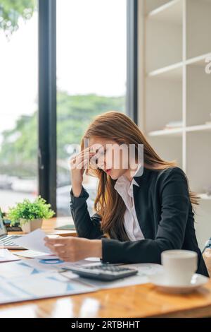 Les femmes d'affaires asiatiques sont le stress tout en travaillant sur ordinateur portable, femme d'affaires fatiguée avec mal à la tête au bureau, se sentant malade au travail Banque D'Images
