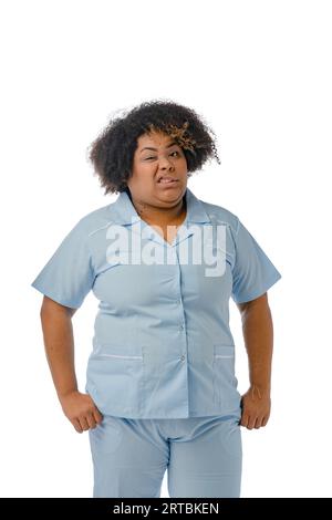 Portrait vertical d'une jeune femme afro-latino d'origine vénézuélienne, portant un uniforme bleu, infirmière debout froissée caméra dans le dégoût et regardant Banque D'Images