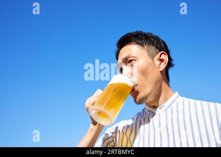 Homme japonais buvant de la bière Banque D'Images