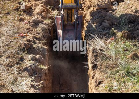 Petite pelle creusant un fossé de tranchée pour une fondation de bâtiment Banque D'Images