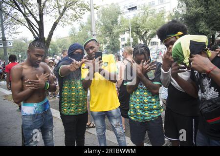 Équipage de jeunes hommes qui se promènent au défilé. Spectateurs le long de Eastern Parkway à la West Indian Caribbean Parade annuelle le jour du travail à Brooklyn, New York. Banque D'Images