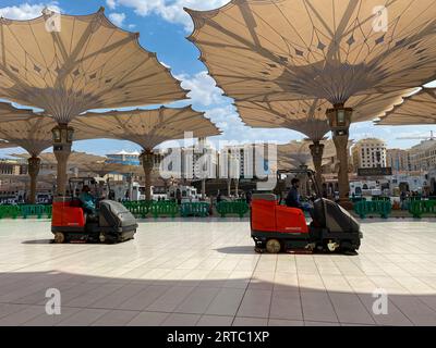 Medina, Arabie Saoudite - 22 août 2023 : des pèlerins marchent sous des parapluies géants dans l'enceinte de la mosquée Nabawi. Auvents à Masjid Nabawi à Médine, en Arabie saoudite Banque D'Images