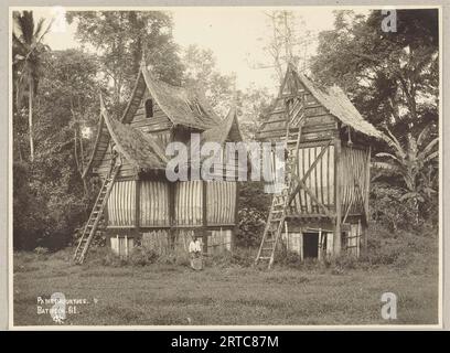 West Sumatra, Indonésie, 1900, photo d'archives anciennes, deux maisons Minangkabau où le riz est stocké. La partie supérieure est décorée de sculptures en bois et possède des portes, accessibles par une échelle. Banque D'Images