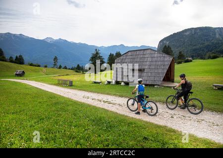 Mère et fils lors d'un voyage à vélo s'arrêtant près d'un bel abri en bois sur une piste cyclable près du lac Bohinj dans le parc national du Triglav, Slovénie Banque D'Images