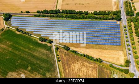 Vue aérienne d'un système monté au sol avec modules photovoltaïques à côté d'une route et d'une voie ferrée, Hesse, Allemagne Banque D'Images