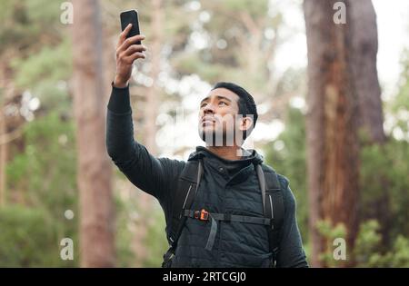 Téléphone, connexion et homme perdu dans la nature pour la randonnée, le trekking et l'exercice dans les bois. Fitness, voyage et personne sur smartphone sans signal GPS Banque D'Images