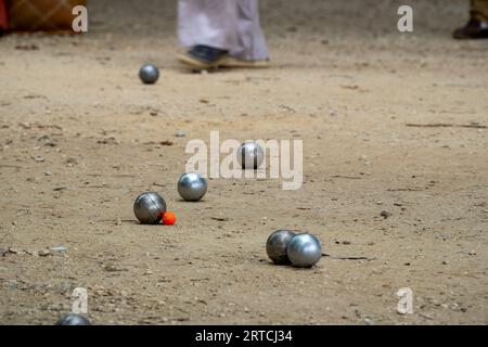Bols de boules de pétanque sur un sol poussiéreux, photo en impact. Jeu de pétanque au sol. Balles et un petit cric en bois. Banque D'Images