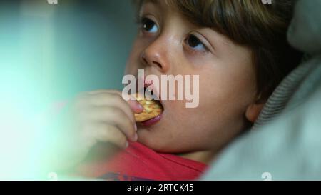 Child's Delight - Close-Up expression of Boy comme il aime un cookie snack Banque D'Images