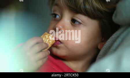 Child's Delight - Close-Up expression of Boy comme il aime un cookie snack Banque D'Images