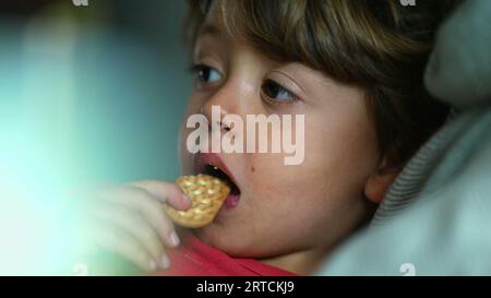 Child's Delight - Close-Up expression of Boy comme il aime un cookie snack Banque D'Images