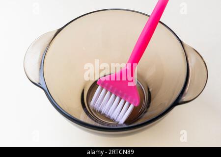 fille dans des gants de protection en caoutchouc bleu tenant une brosse dans ses mains et remuant colorant capillaire gros plan coloriste soins capillaires au masque capillaire à la maison. Banque D'Images