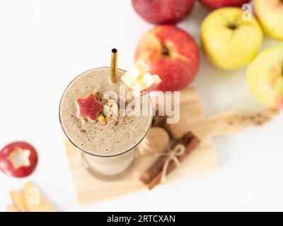 Smoothie aux pommes avec cannelle, avoine et noix sur fond blanc avec des pommes rouges et vertes. Vue du dessus de la table. Gros plan. Petit déjeuner d'automne à base de plantes. Banque D'Images