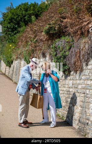 couple âgé habillé intelligemment regardant dans un sac et parlant alors qu'il est dehors pour une promenade ensemble sur une journée ensoleillée. Banque D'Images